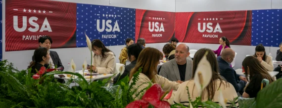 Beauty professionals meeting around tables inside an international country pavilion.