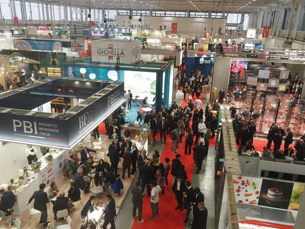 An elevated view across the busy MARCA 2026 show floor, with red aisles, exhibition stands and the pavilion roof in view.