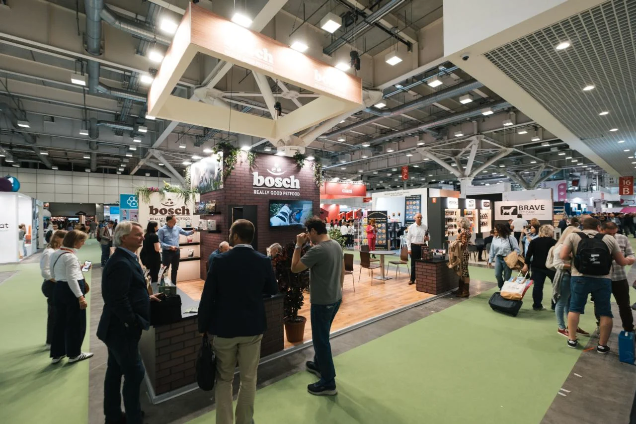 A broad Zoomark 2025 exhibition hall with trade visitors, constructed stands and the pavilion structure visible above.